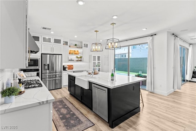 3369 Ponicelli Ln, Henderson, NV 89044 - kitchen featuring stainless steel appliances, white cabinetry, light wood-type flooring, wall chimney range hood, and glass insert cabinets