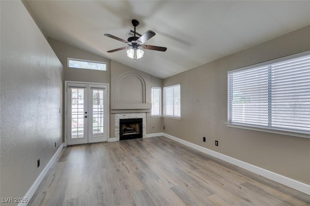 87 Ginger Lily Ter, Henderson, NV 89074 - unfurnished living room featuring lofted ceiling, a ceiling fan, light wood-style floors, french doors, and a fireplace