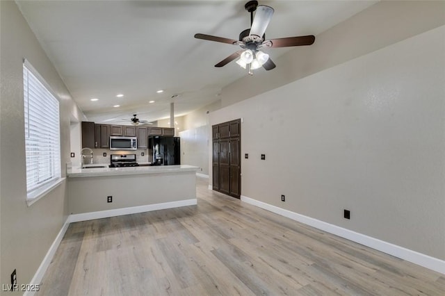 87 Ginger Lily Ter, Henderson, NV 89074 - kitchen with stainless steel appliances, a ceiling fan, vaulted ceiling, a peninsula, and light wood-type flooring