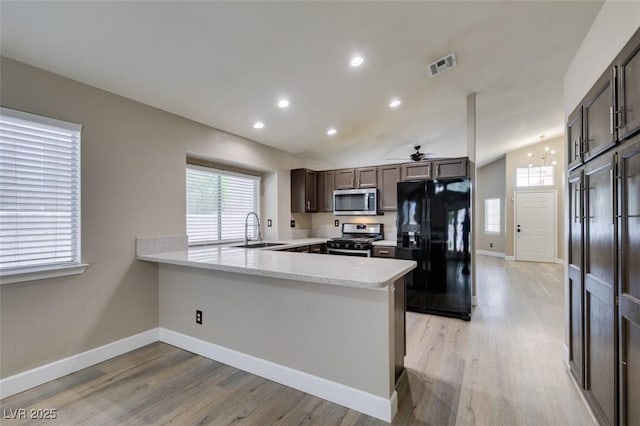 87 Ginger Lily Ter, Henderson, NV 89074 - kitchen with stainless steel appliances, dark brown cabinetry, a peninsula, light wood finished floors, and lofted ceiling