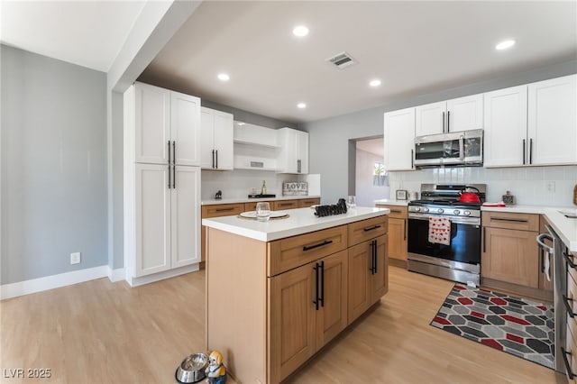 915 Melrose Dr, Las Vegas, NV 89101 - kitchen with appliances with stainless steel finishes, light wood-style flooring, open shelves, a kitchen island, and backsplash