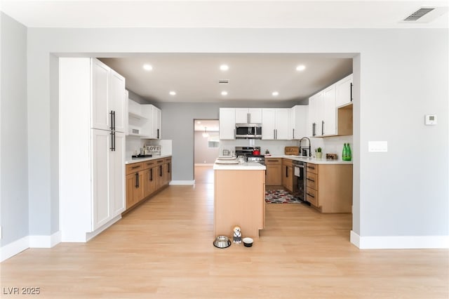 915 Melrose Dr, Las Vegas, NV 89101 - kitchen featuring appliances with stainless steel finishes, a center island with sink, light wood-type flooring, recessed lighting, and light countertops