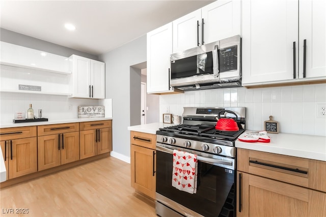 915 Melrose Dr, Las Vegas, NV 89101 - kitchen featuring stainless steel appliances, light countertops, open shelves, light wood-style flooring, and tasteful backsplash