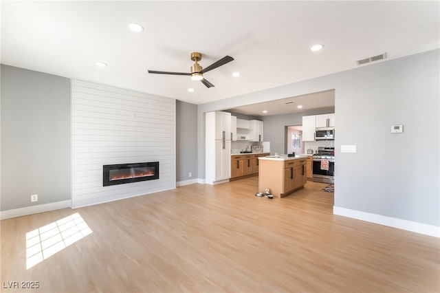 915 Melrose Dr, Las Vegas, NV 89101 - unfurnished living room featuring a ceiling fan, light wood-style floors, a large fireplace, and recessed lighting