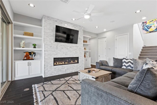6338 Skystone St, Las Vegas, NV 89135 - living area with dark wood-style flooring, built in features, ceiling fan, a stone fireplace, and stairs