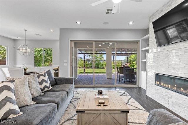 6338 Skystone St, Las Vegas, NV 89135 - living room featuring wood-type flooring, a glass covered fireplace, ceiling fan, recessed lighting, and built in shelves