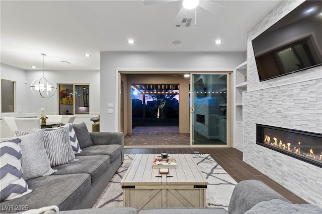 6338 Skystone St, Las Vegas, NV 89135 - living area with wood finished floors, a stone fireplace, ceiling fan, a chandelier, and recessed lighting