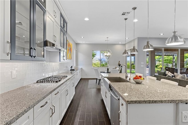 6338 Skystone St, Las Vegas, NV 89135 - kitchen featuring appliances with stainless steel finishes, dark wood-style floors, glass insert cabinets, a large island, and light stone countertops