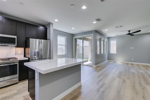 649 Tranquil Jade St, Las Vegas, NV 89138 - kitchen featuring appliances with stainless steel finishes, dark cabinetry, open floor plan, a kitchen island, and light wood-type flooring