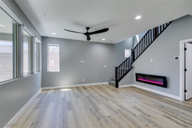 649 Tranquil Jade St, Las Vegas, NV 89138 - unfurnished living room featuring ceiling fan, light wood-style flooring, stairway, recessed lighting, and a glass covered fireplace