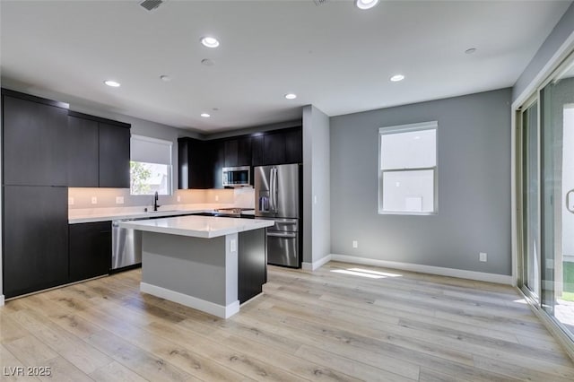 649 Tranquil Jade St, Las Vegas, NV 89138 - kitchen with stainless steel appliances, dark cabinets, a center island, light countertops, and light wood finished floors