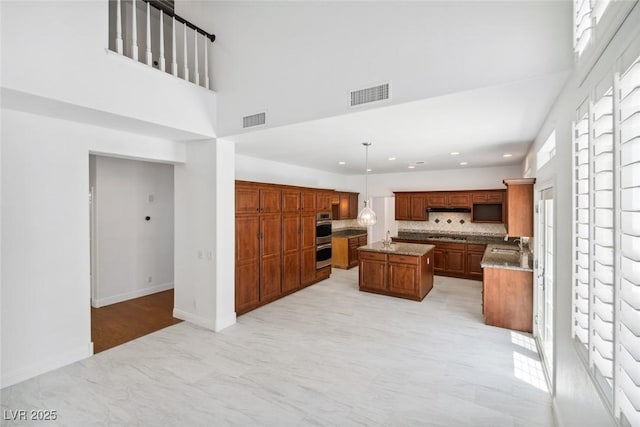 8113 Blue Cascade Ave, Las Vegas, NV 89128 - kitchen featuring a kitchen island, recessed lighting, tasteful backsplash, brown cabinets, and a towering ceiling