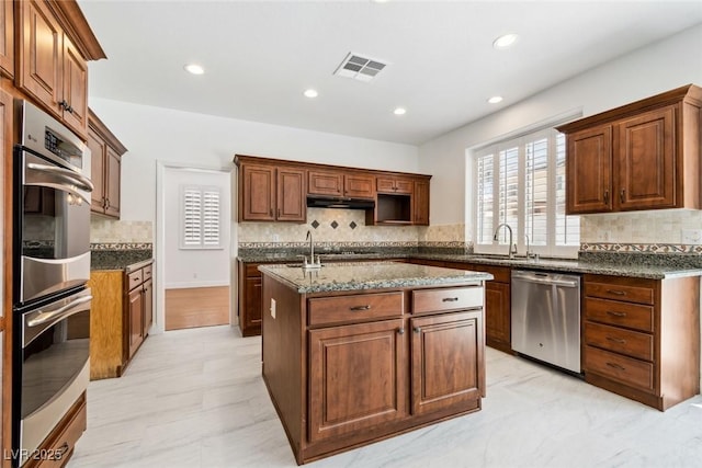 8113 Blue Cascade Ave, Las Vegas, NV 89128 - kitchen featuring appliances with stainless steel finishes, tasteful backsplash, under cabinet range hood, a kitchen island with sink, and recessed lighting