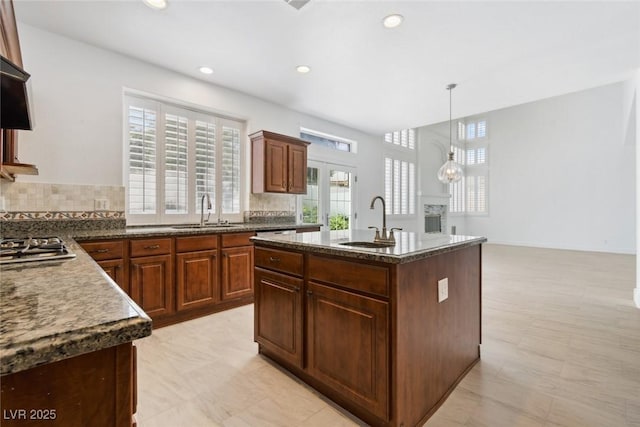 8113 Blue Cascade Ave, Las Vegas, NV 89128 - kitchen with backsplash, stainless steel gas cooktop, a center island with sink, recessed lighting, and decorative light fixtures