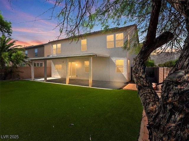 4905 Apache Valley Ave, Las Vegas, NV 89131 - back of house at dusk with a fenced backyard, stucco siding, and a patio