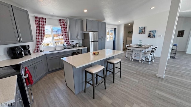 2530 Commercial Dr, Pahrump, NV 89048 - kitchen with stove, freestanding refrigerator, gray cabinetry, a breakfast bar area, and recessed lighting