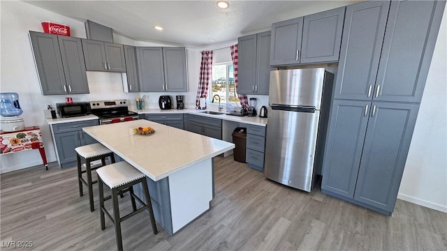 2530 Commercial Dr, Pahrump, NV 89048 - kitchen featuring appliances with stainless steel finishes, a breakfast bar, light wood-style flooring, light countertops, and a center island