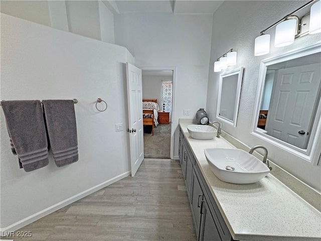 2530 Commercial Dr, Pahrump, NV 89048 - bathroom featuring double vanity, ensuite bath, wood finished floors, and a high ceiling