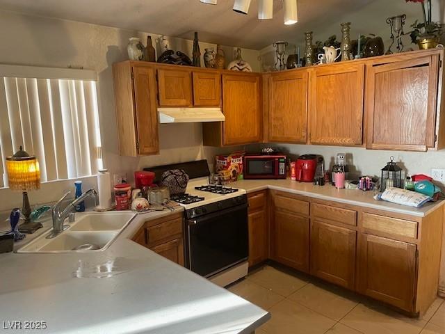 5429 Chela Dr, Las Vegas, NV 89120 - kitchen with gas range gas stove, under cabinet range hood, light countertops, light tile patterned flooring, and brown cabinetry