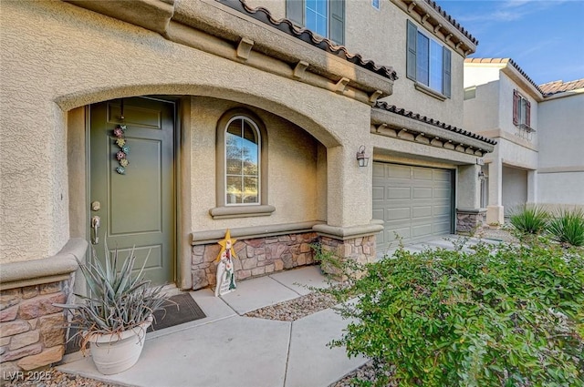 9715 Aleutian St, Las Vegas, NV 89178 - view of exterior entry featuring an attached garage, stone siding, stucco siding, and a tiled roof
