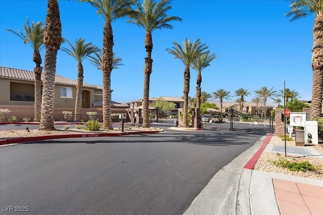 6868 Sky Pointe Dr Unit 2035, Las Vegas, NV 89131 - view of asphalt road with a gate, sidewalks, curbs, a gated entry, and traffic signs