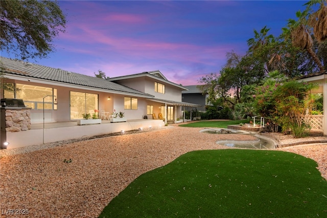 226 Dalmatian Ln, Las Vegas, NV 89107 - rear view of house featuring stucco siding, a patio, a yard, and a tiled roof