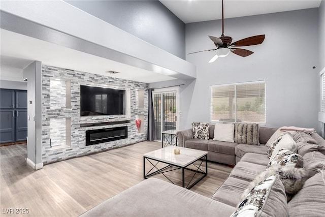 3825 Manhattan Bridge Pl, North Las Vegas, NV 89032 - living room with ceiling fan, a fireplace, wood finished floors, and a towering ceiling