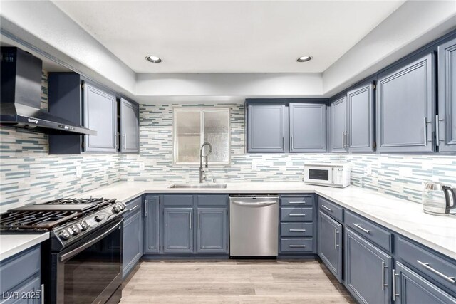 3825 Manhattan Bridge Pl, North Las Vegas, NV 89032 - kitchen with appliances with stainless steel finishes, wall chimney range hood, tasteful backsplash, light wood-type flooring, and recessed lighting