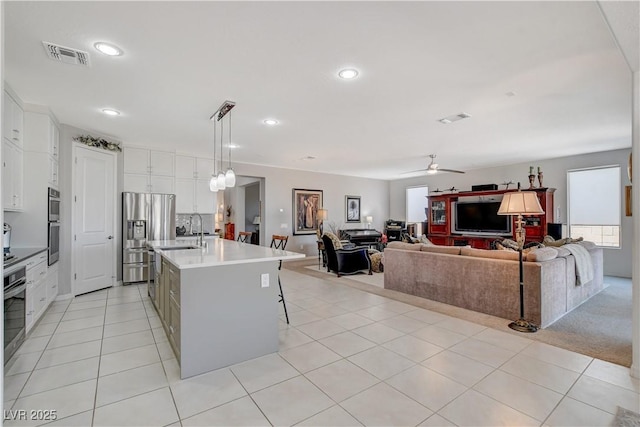8286 Skye Gorge St, Las Vegas, NV 89166 - kitchen with stainless steel fridge, ceiling fan, white cabinets, a kitchen island with sink, and pendant lighting