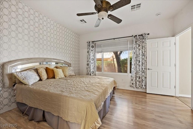 2117 Bay Thrush Way N, Las Vegas, NV 89084 - bedroom featuring wallpapered walls, light wood-style floors, ceiling fan, and an accent wall