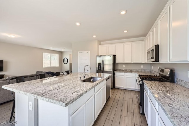 5606 Verde Valley Ct, North Las Vegas, NV 89081 - kitchen with appliances with stainless steel finishes, open floor plan, a kitchen bar, white cabinets, and recessed lighting
