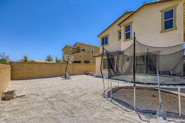 5606 Verde Valley Ct, North Las Vegas, NV 89081 - rear view of house with a trampoline, a fenced backyard, and stucco siding