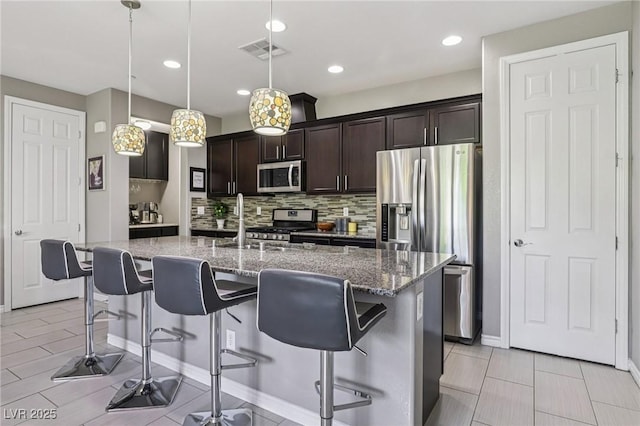 1922 Via Delle Arti, Henderson, NV 89044 - kitchen featuring appliances with stainless steel finishes, decorative backsplash, dark brown cabinets, a breakfast bar area, and recessed lighting