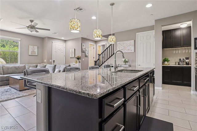 1922 Via Delle Arti, Henderson, NV 89044 - kitchen with ceiling fan, light tile patterned floors, an island with sink, stone counters, and recessed lighting