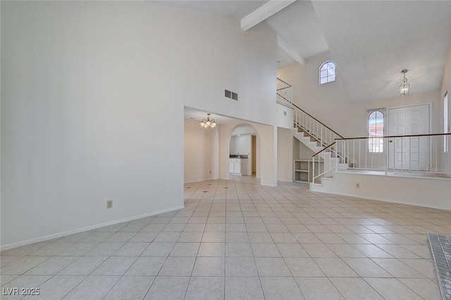 8809 Beach Front Dr, Las Vegas, NV 89117 - unfurnished living room with light tile patterned floors, arched walkways, beamed ceiling, stairway, and a chandelier