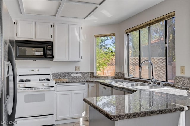 8809 Beach Front Dr, Las Vegas, NV 89117 - kitchen with black microwave, white gas stove, dark stone countertops, dishwashing machine, and a peninsula