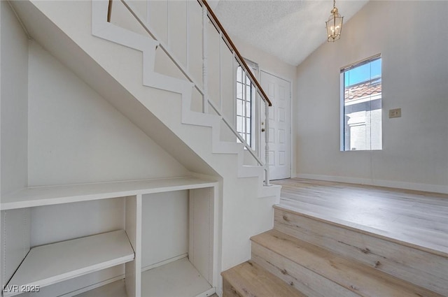 8809 Beach Front Dr, Las Vegas, NV 89117 - stairs featuring lofted ceiling, wood finished floors, and a textured ceiling