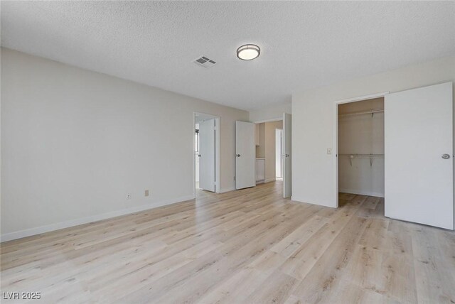 8809 Beach Front Dr, Las Vegas, NV 89117 - unfurnished bedroom featuring light wood finished floors, a spacious closet, a textured ceiling, and a closet