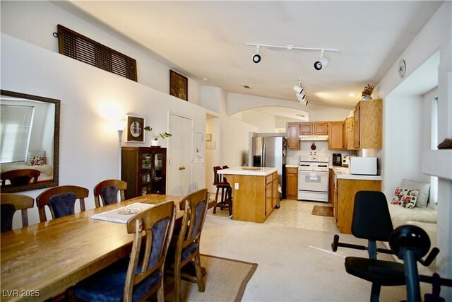 6131 Pumpkin Patch Ave, Las Vegas, NV 89142 - dining room with rail lighting, light carpet, vaulted ceiling, and arched walkways