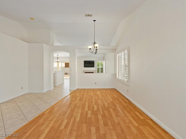 4323 Pageantry Falls Dr, North Las Vegas, NV 89031 - empty room featuring a chandelier, vaulted ceiling, light wood finished floors, and arched walkways