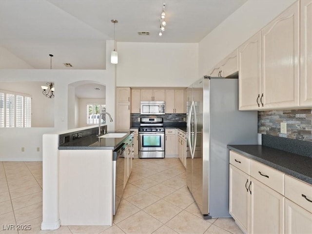4323 Pageantry Falls Dr, North Las Vegas, NV 89031 - kitchen with appliances with stainless steel finishes, light tile patterned flooring, decorative backsplash, and arched walkways