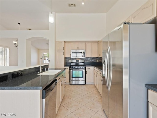 4323 Pageantry Falls Dr, North Las Vegas, NV 89031 - kitchen featuring appliances with stainless steel finishes, light tile patterned floors, arched walkways, decorative backsplash, and pendant lighting