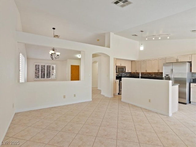 4323 Pageantry Falls Dr, North Las Vegas, NV 89031 - kitchen featuring appliances with stainless steel finishes, arched walkways, tasteful backsplash, light tile patterned floors, and high vaulted ceiling