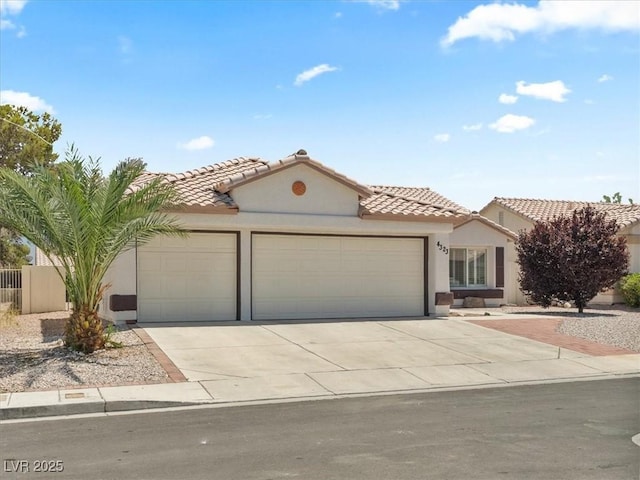 4323 Pageantry Falls Dr, North Las Vegas, NV 89031 - mediterranean / spanish home featuring an attached garage, concrete driveway, a tiled roof, and stucco siding