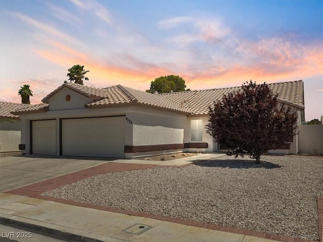 4323 Pageantry Falls Dr, North Las Vegas, NV 89031 - view of front of house featuring a garage, a tile roof, concrete driveway, and stucco siding