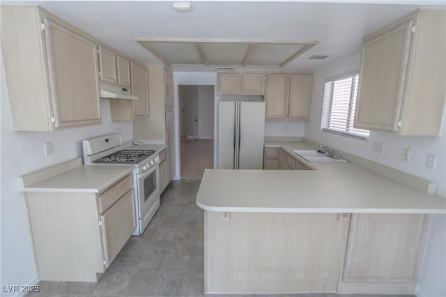1349 Goldenglow Rd, Las Vegas, NV 89108 - kitchen featuring white gas range, freestanding refrigerator, light brown cabinetry, under cabinet range hood, and light countertops