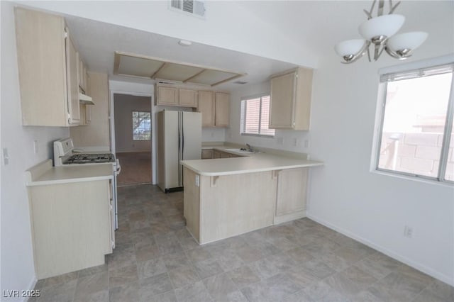 1349 Goldenglow Rd, Las Vegas, NV 89108 - kitchen featuring range with gas stovetop, freestanding refrigerator, light brown cabinets, a peninsula, and light countertops
