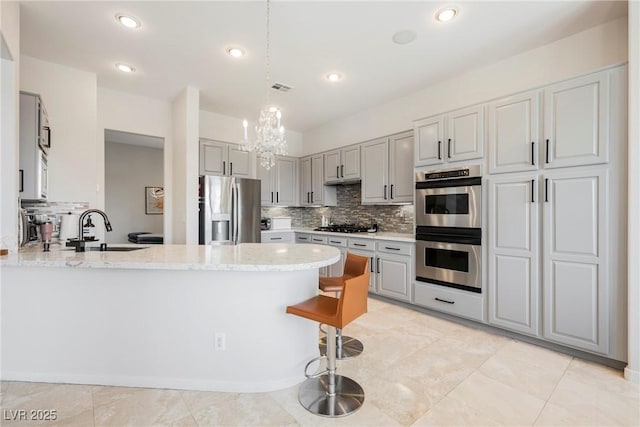 3042 Soft Horizon Way, Las Vegas, NV 89135 - kitchen with appliances with stainless steel finishes, a peninsula, a chandelier, decorative backsplash, and recessed lighting