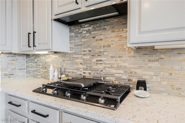 3042 Soft Horizon Way, Las Vegas, NV 89135 - kitchen with black gas stovetop, under cabinet range hood, backsplash, and white cabinets