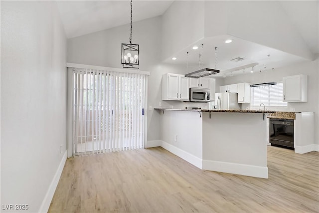 2925 Wigwam Pkwy Unit 1021, Henderson, NV 89074 - kitchen featuring appliances with stainless steel finishes, light wood finished floors, white cabinetry, a breakfast bar area, and a peninsula